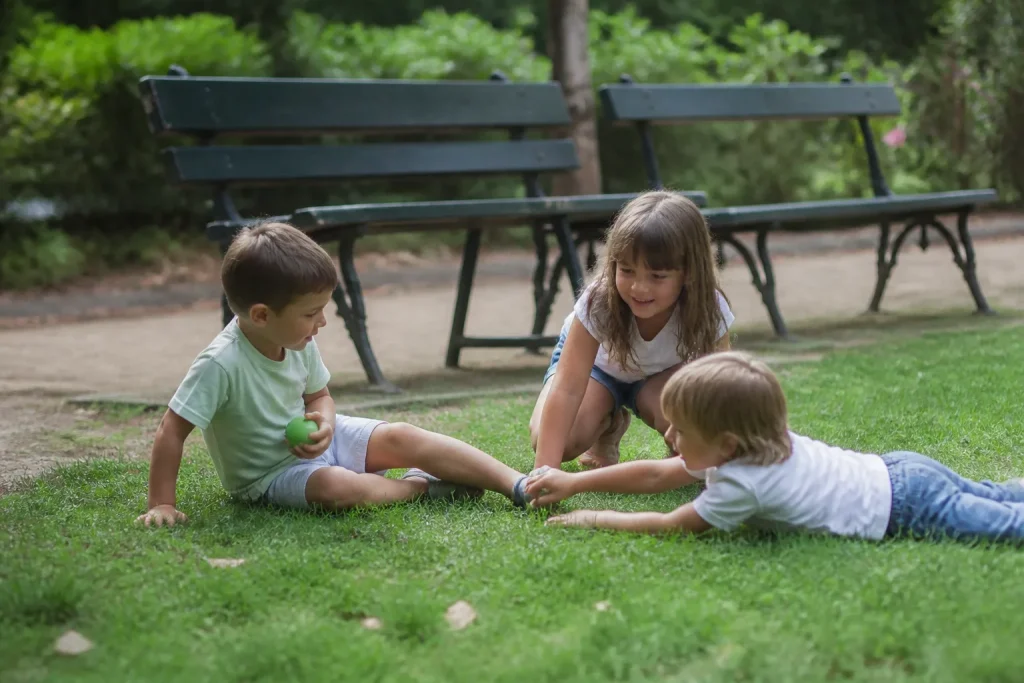 Enfants jouant sur la pelouse devant des bancs