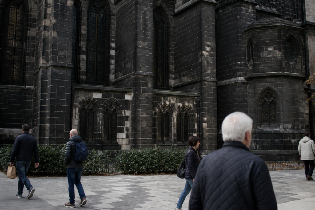 Passants devant la cathedrale en pierre noire de lave